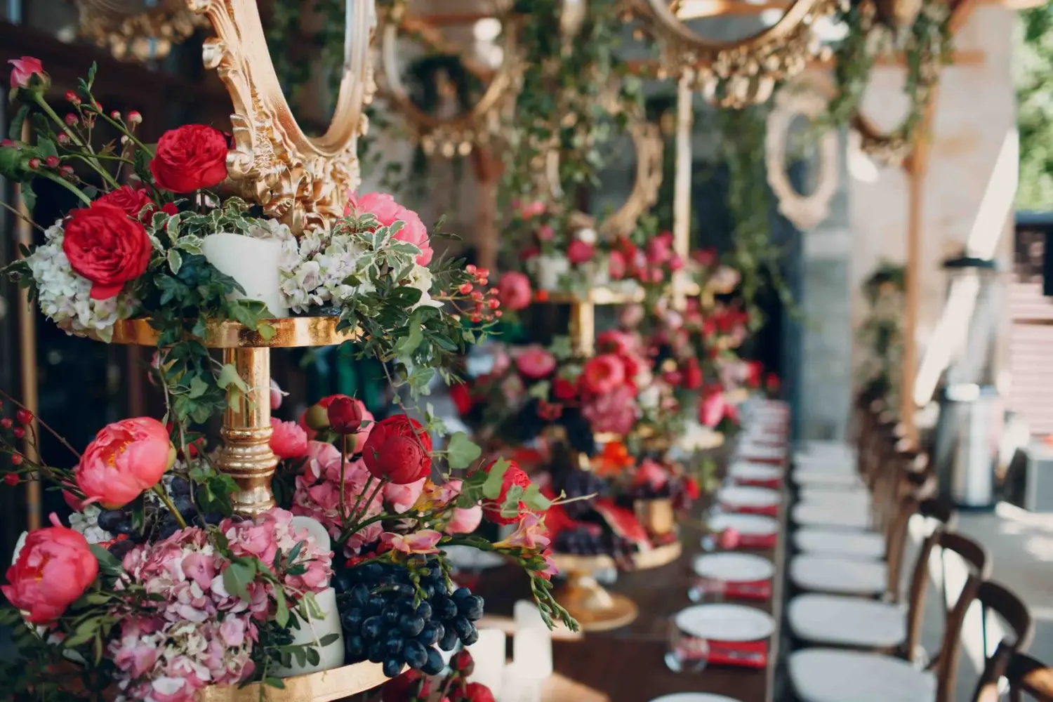 Hochzeitstischdekoration mit Blumen, Früchten und Beeren in den Farben Rot, Weiß, Rosa und Grün.